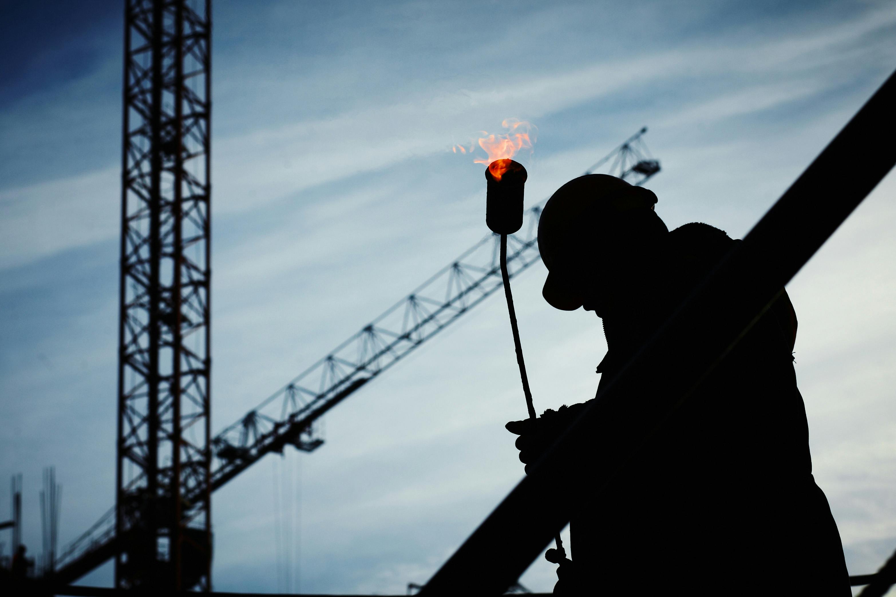 Welder silhouette with torch at construction site